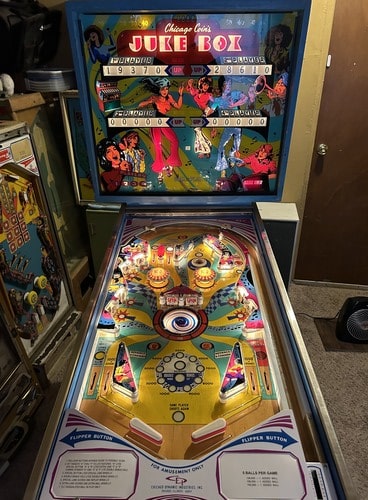 Face-on view of a Chicago Coin Jukebox pinball machine, with the playfield and marquee lit up.