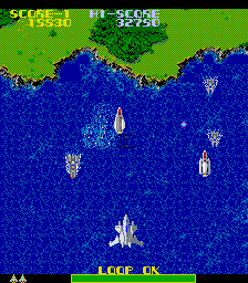 Another screenshot of the game Wyvern F-0. A top-down shooter showing a fighter jet above water, with a green shoreline at the top.