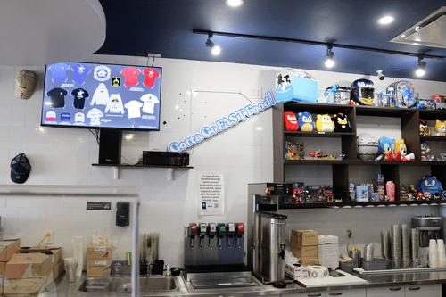 Wall behind the service counter at the Sonic Speed Cafe, showing a wide variety of Sonic memorabilia on the shelves. 