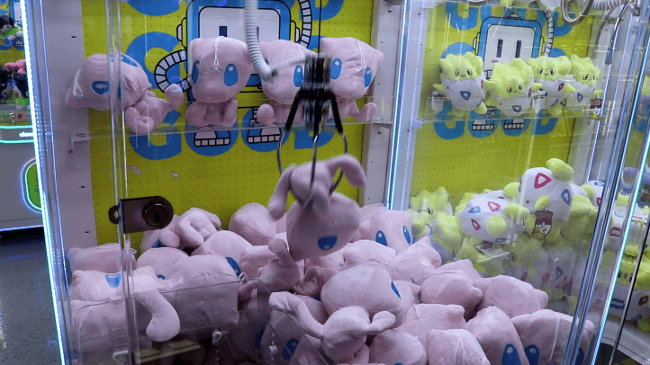 Victory! AT & Sam claim a knockoff Mew plushie as a prize. In the adjacent claw machine, numerous Togepi dolls can be seen.